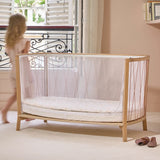 Geöffnetes Babybett KIMI von Charlie Crane in Bois de Rose Farbton mit Kind
