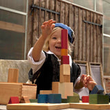 Kind am Spielen mit 30-teiligem Set an Holzbauklötzen in Regenbogenfarbe von Wooden Story