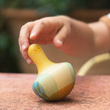 Kinderhand mit Holzkreisel Flowing Yellow Bird von Grapat