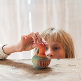 Kind mit Grapat Holzkreisel Mellow Orange Bird