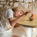 Kind sitzt an Tisch mit Grapat Holzkreisel Mellow Orange Bird