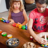 Kinder beim Spielen mit Grapat Schälchen und Eicheln in Regenbogenfarben