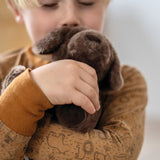 Kind kuschelt mit Plüschtier-Hund von small foot