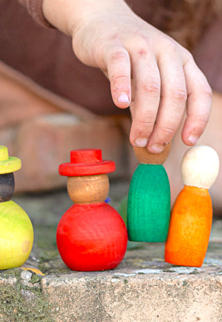 Kind das mit bunten Holzfiguren spielt